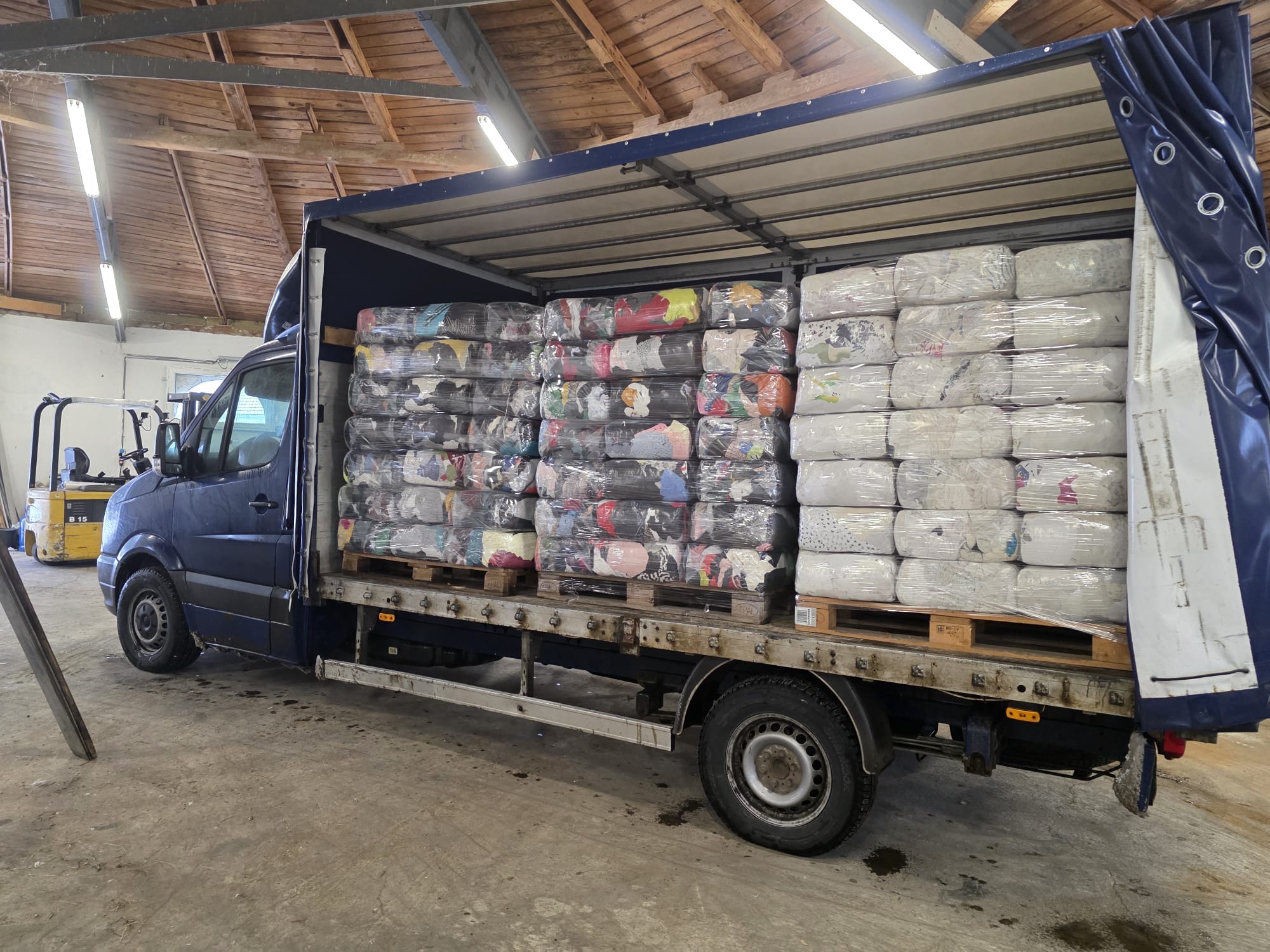 Dodávka naložená lisovanými balíkmi handier v sklade